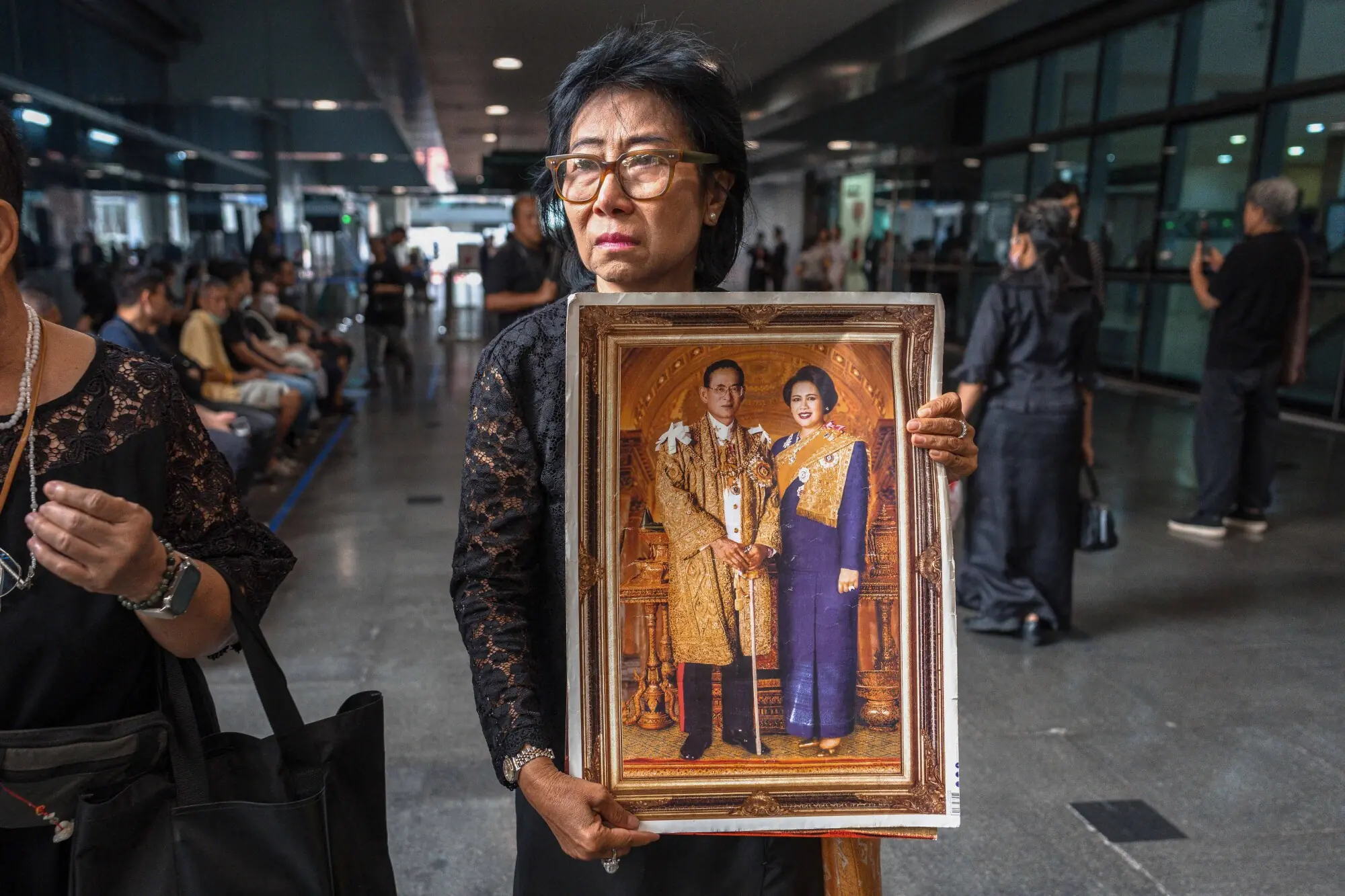     Thai mourner Kanjana Malaithong holds portraits of Thailand's former queen Sirikit as she walks at Bangkok's Chulalongkorn hospital on October 25. — AFP