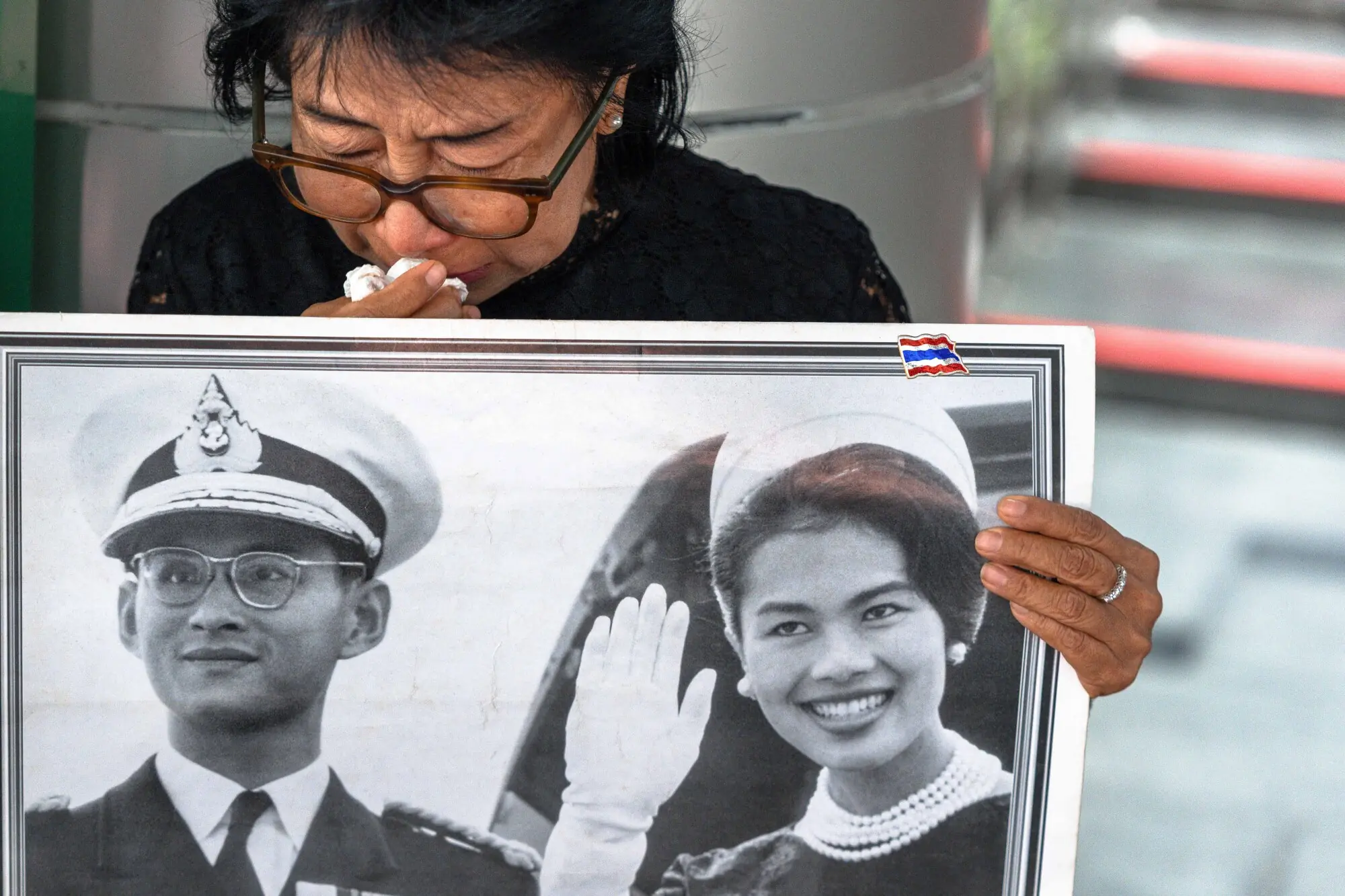    Thai mourner Kanjana Malaithong holds a portrait of former Thai Queen Sirikit and Thai King Bhumibol Adulyadej as she mourns at Bangkok's Chulalongkorn Hospital on October 25. — AFP 