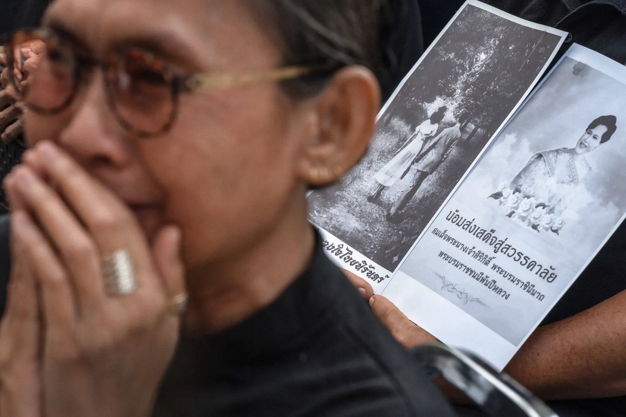     A Thai mourner holds a photograph of Thailand's former queen Sirikit as another cries at Bangkok's Chulalongkorn hospital on October 25. — AFP 