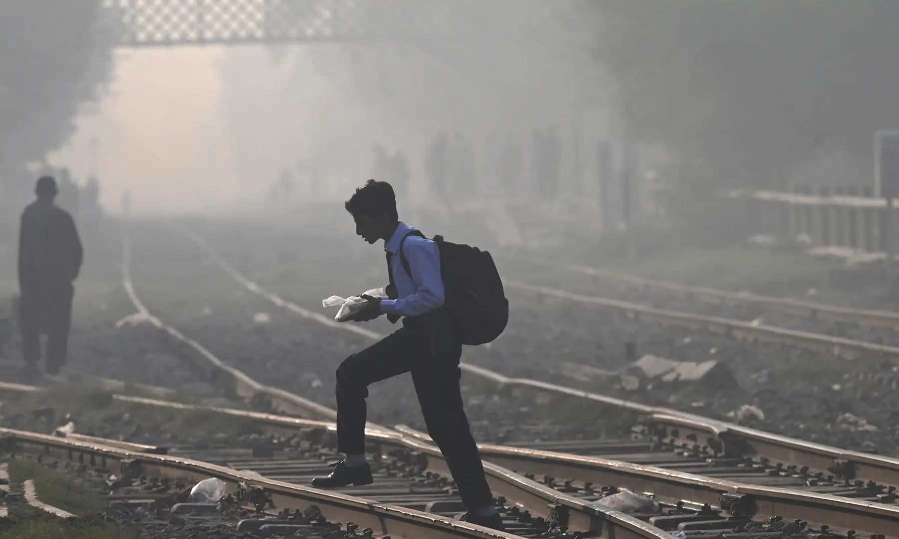 A schoolboy crosses a train track amid pollution in Lahore on October 25. — AFP