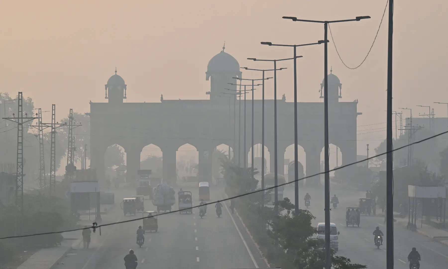 Commuters travel along a highway amid smoggy conditions in Lahore on October 24. — AFP