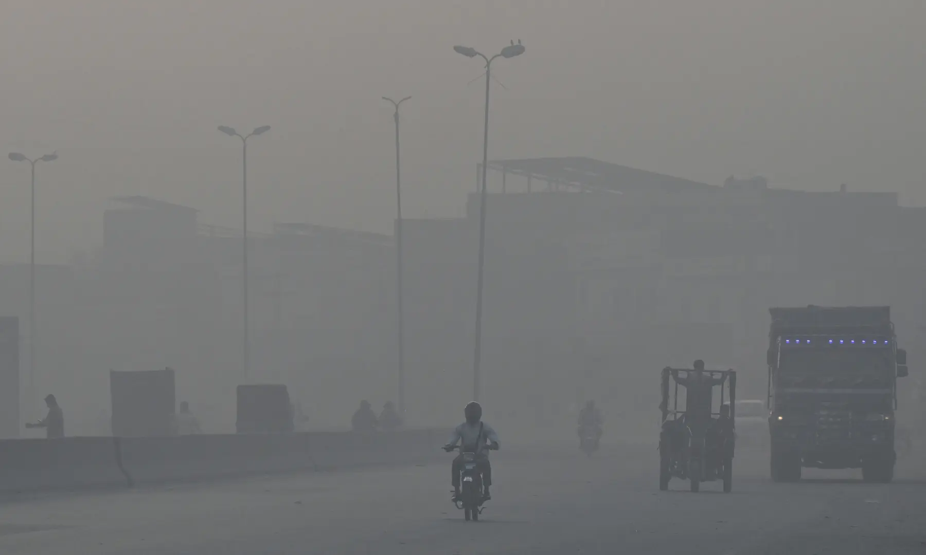 Commuters travel along a highway amid smoggy conditions in Lahore on October 24. — AFP