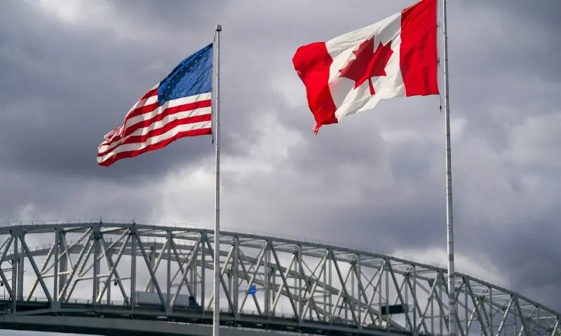 The US and Canada flags flutter next to the Blue Water Bridge border crossing in Point Edward, Ontario, on October 24. &mdash;AFP