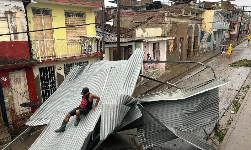 A resident slides on part of the roof of his home, damaged by Hurricane Melissa, in Santiago de Cuba, Cuba, on October 29. — AFP