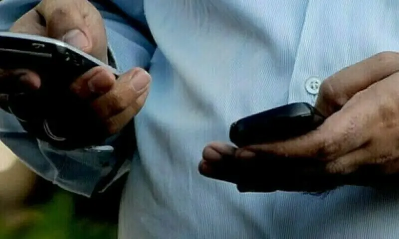 An undated file photo of a pair of hands holding two mobile phones. &mdash; AFP/File