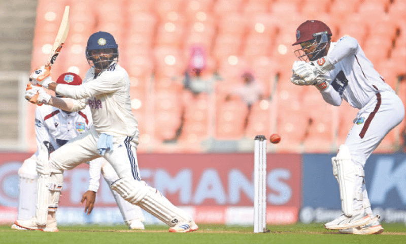 INDIAN batter Ravindra Jadeja plays a shot as West Indies wicket-keeper Shai Hope looks on during the first Test at the Narendra Modi Stadium on Friday.&mdash;AFP