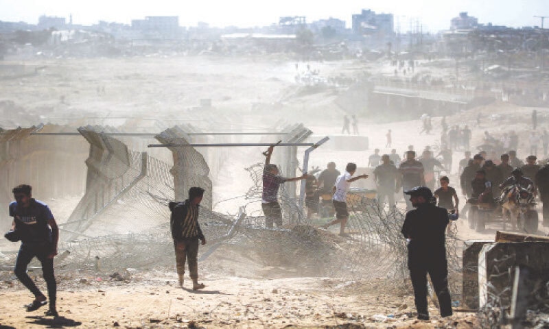 A MAN attempts to remove the fence and barriers at the so-called &lsquo;Netzarim corridor&rsquo; near Nuseirat in the central Gaza Strip on Friday, as people make their way back to Gaza City.&mdash;AFP