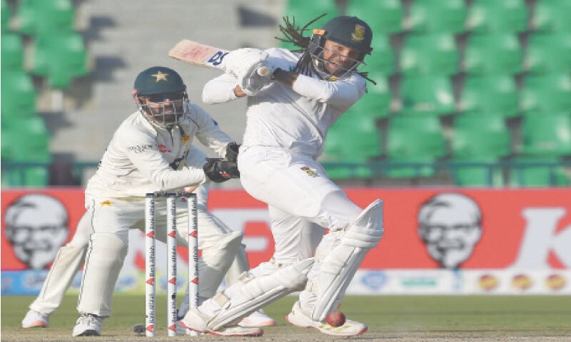 SOUTH African batter Tony de Zorzi plays a stroke as Pakistan wicket-keeper Mohammad Rizwan looks on during the first Test at the Gaddafi Stadium on Monday.—M. Arif/White Star