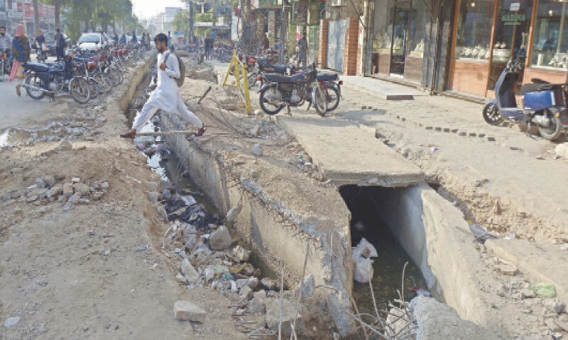 A student walks on a plank to cross a dug-up portion of Sixth Road in Rawalpindi on Wednesday. &mdash; White Star