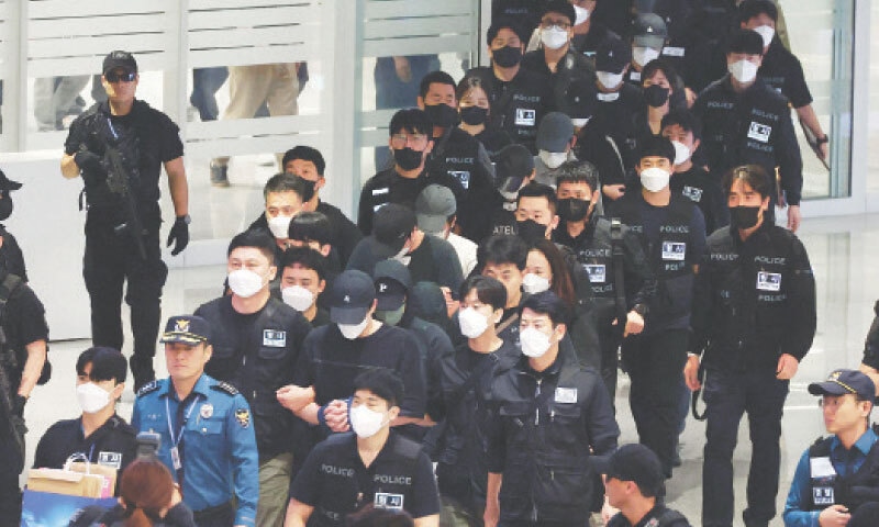 Police officers escort repatriated South Koreans upon their arrival at Incheon international airport on Saturday.—AFP Police officers escort repatriated South Koreans upon their arrival at Incheon international airport on Saturday.—AFP
