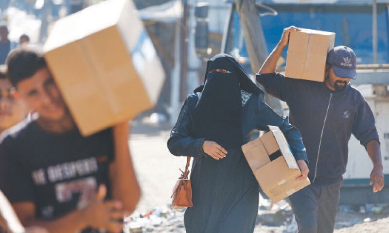 CENTRAL GAZA STRIP: Palestinians carry home boxes of aid supplies that trickled into Gaza, amid a fragile ceasefire with Israel.&mdash;Reuters