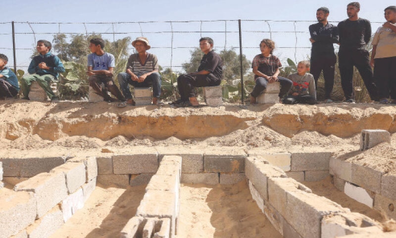 CENTRAL GAZA: Children watch as the remains of Palestinians, returned by Israel, are brought to a cemetery to be interred in Deir al-Balah.&mdash;AFP