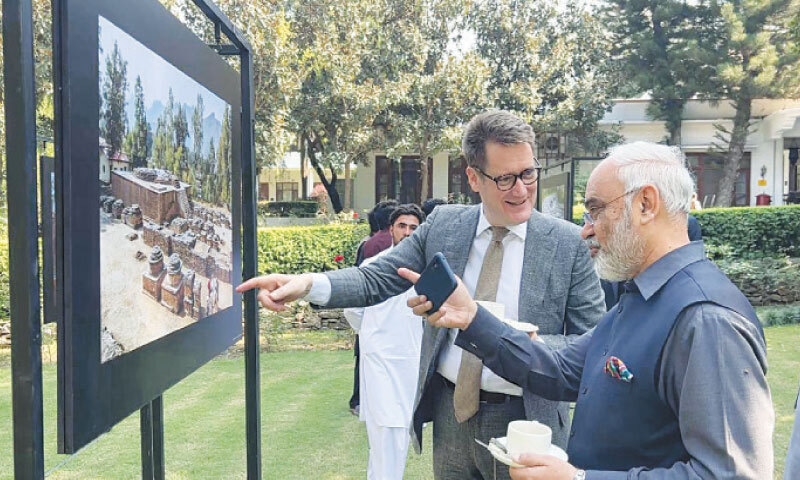 Participants of the ceremony take interest in photographs of archaeological sites. &mdash; Dawn