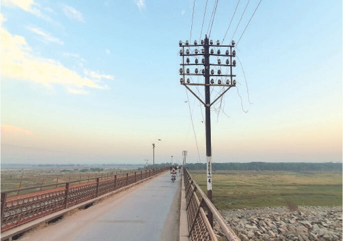 Broken cables dangle from the telephone poles of the railway network along an old bridge.
