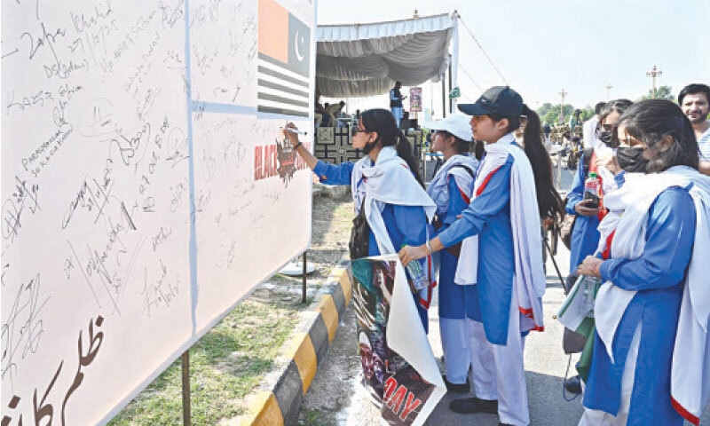 Students sign a board to express solidarity with Kashmiris on Black Day after marching from Foreign Office to D-Chowk in Islamabad on Monday. &mdash; APP