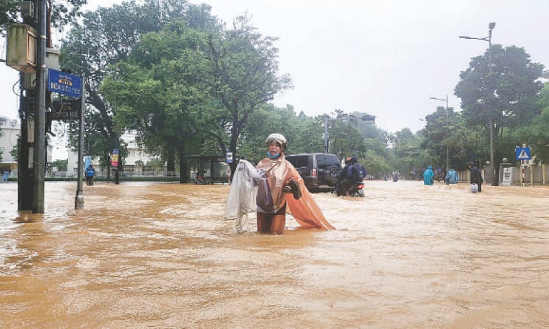 HUE: A woman wearing a raincoat wades through a flooded street. Vietnam&rsquo;s environment ministry recorded more than a metre of rainfall on Tuesday.&mdash;AFP