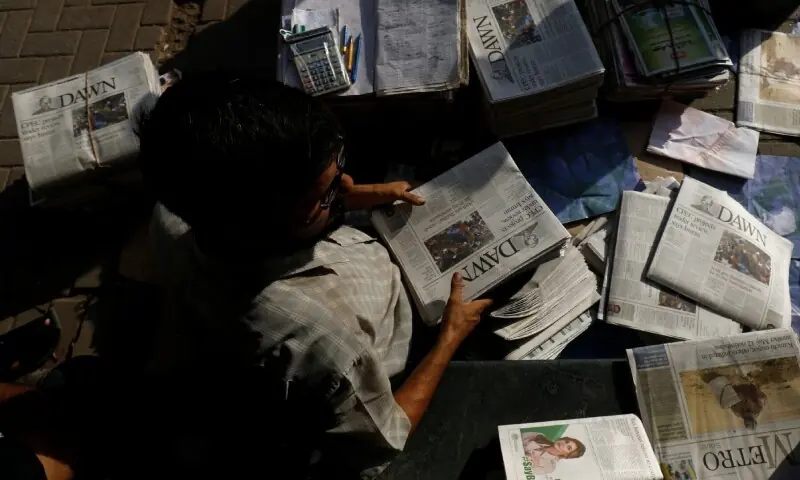 A hawker sorts out newspapers as he sells them along a street in Karachi on October 7, 2018. &mdash; Reuters