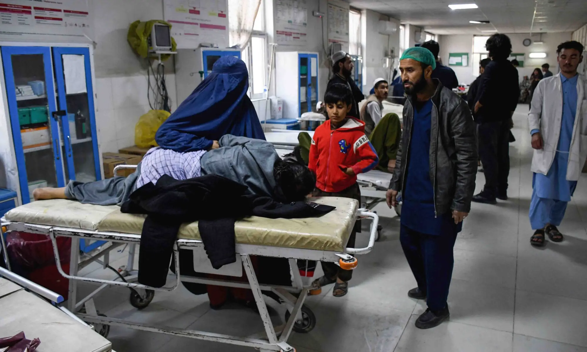 An Afghan woman sits beside an earthquake victim receiving treatment at a hospital in Mazar-i-Sharif on November 3, 2025. &mdash; Reuters