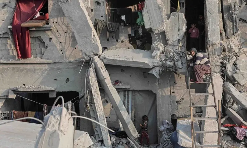 A Palestinian woman sits on a ladder outside her heavily damaged house in Jabalia, in the northern Gaza Strip, on November 7, 2025. &mdash; AFP