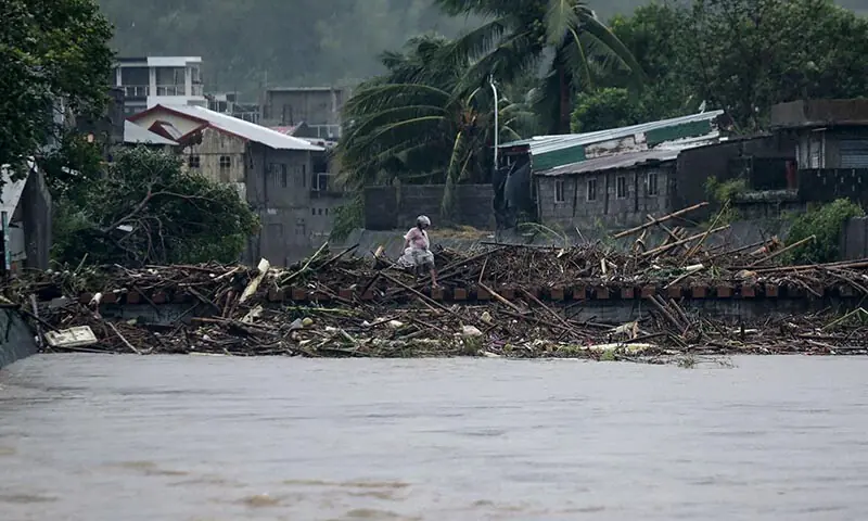 A man walks past debris along the shores of a river at Polangui in Albay province, south of Manila, the Philippines on November 9, after Super Typhoon Fung-wong made landfall. — AFP