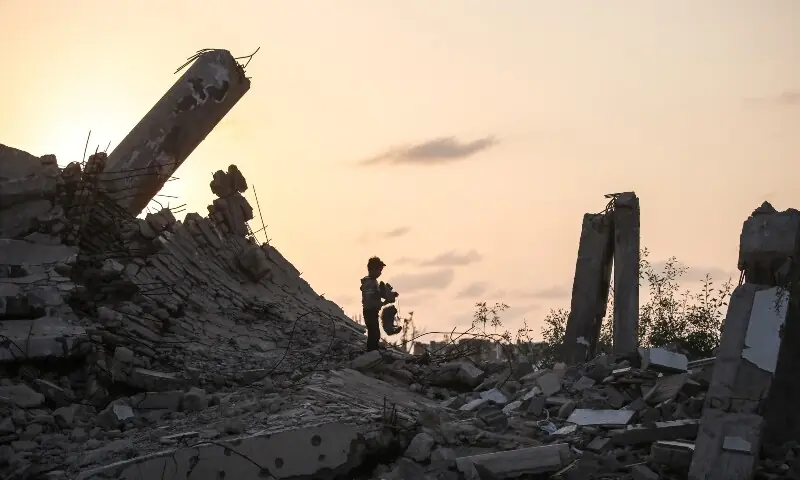 A young Palestinian boy picks up a piece of rubble in Nuseirat, Gaza Strip on November 11. &mdash; AFP