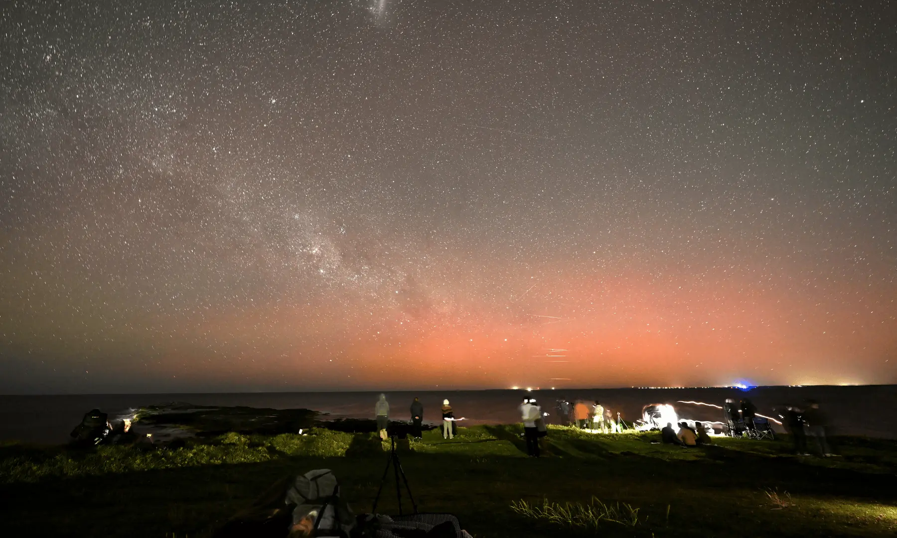 Star gazers gather to watch the Aurora Australis, also known as the Southern Lights, illuminating the night sky at Gerroa Headland in Kiama, around 133 kilometres south of Sydney, on November 12. — AFP