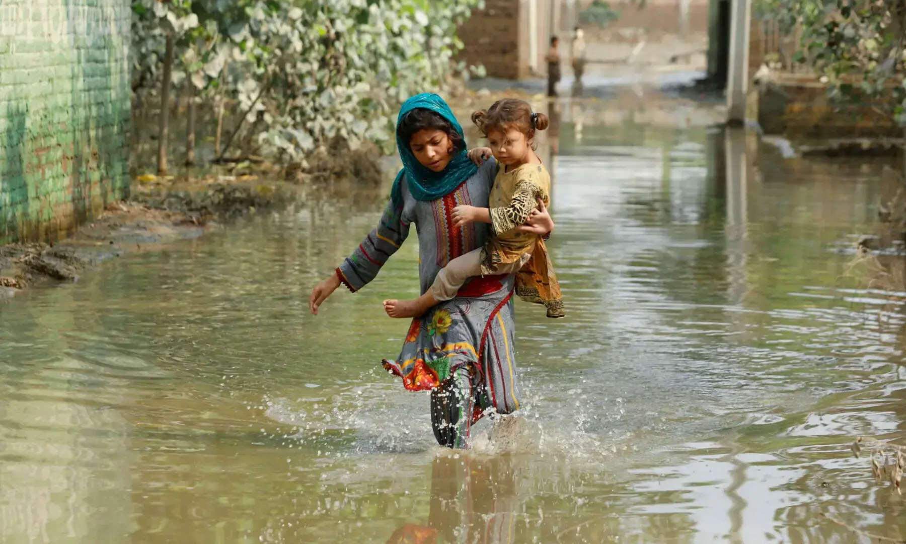 A girl carries her sibling as she walks through stranded flood water in Khyber Pakhtunkhwa’s Nowshera on Sept 4, following rains and floods during the monsoon season. — Reuters A girl carries her sibling as she walks through stranded flood water in Khyber Pakhtunkhwa’s Nowshera on Sept 4, following rains and floods during the monsoon season. — Reuters