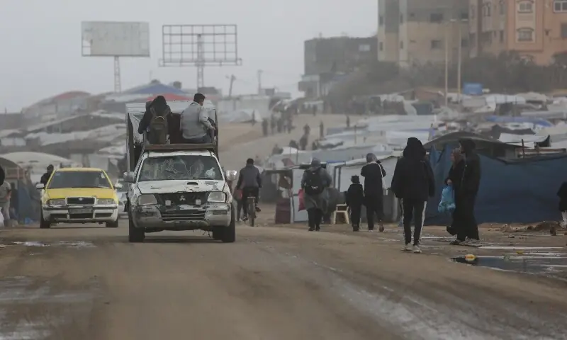 Displaced Palestinian walk past a vehicle carrying others west of Deir al-Balah city in the central Gaza Strip, on November 15, 2025 as a low-pressure system impacts the area. &mdash; AFP