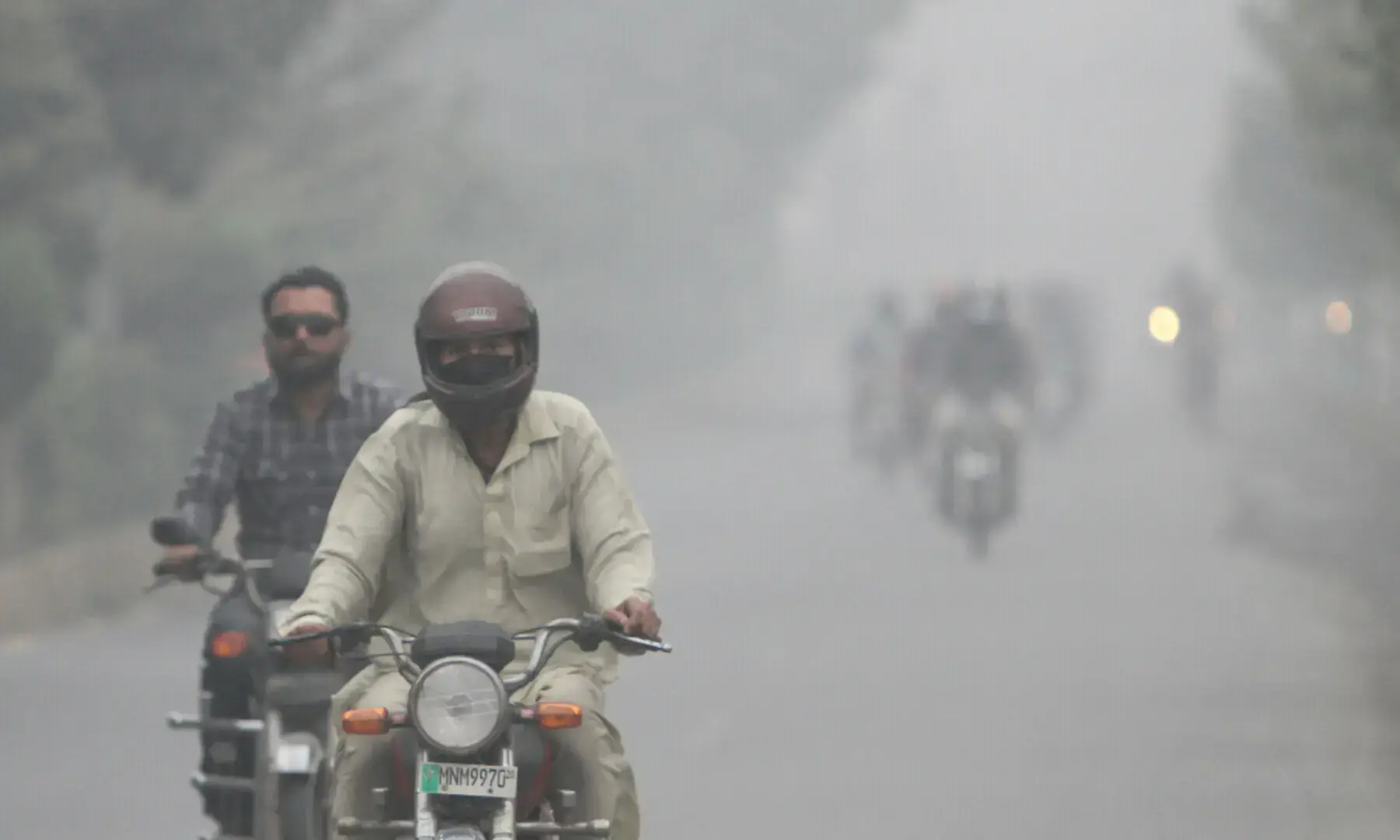 People ride on motorbikes amid smog on a road in Multan on November 12. &mdash; Reuters