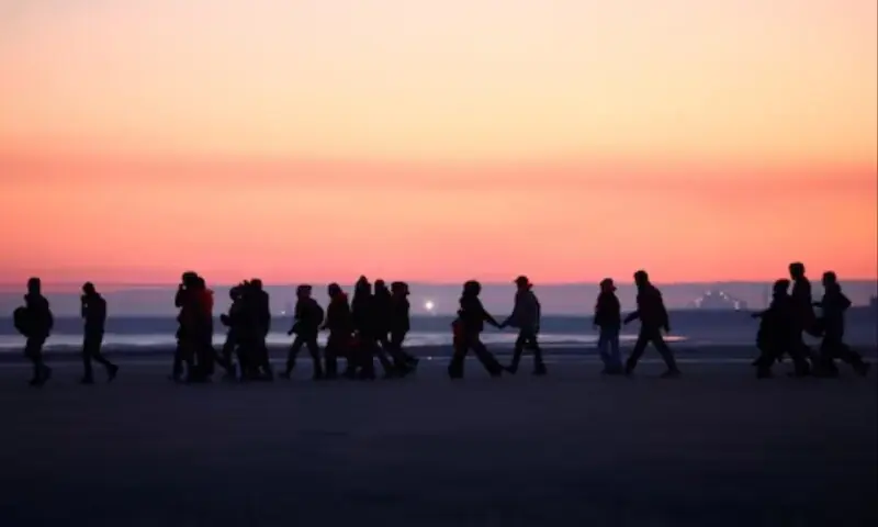 Migrants walk along the beach before trying to board an inflatable dinghy leaving the coast of northern France in an attempt to cross the English Channel to reach Britain, from the beach of Petit-Fort-Philippe in Gravelines, near Calais, France, September 27, 2025. &mdash; Reuters/Abdul Saboo