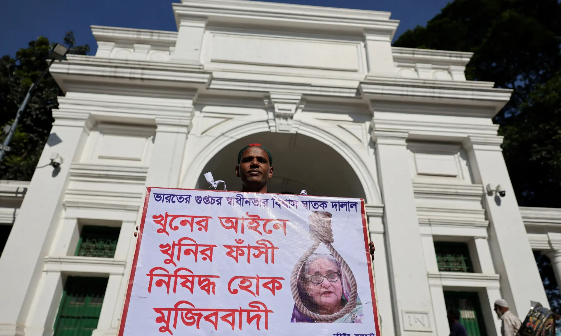 A man holds a poster in front of the court demanding the capital punishment ahead of the verdict on charges of crimes against humanity for a deadly crackdown on student-led protests in 2024 against the ousted Prime Minister Sheikh Hasina, in Dhaka, Bangladesh, on November 17, 2025. — Reuters