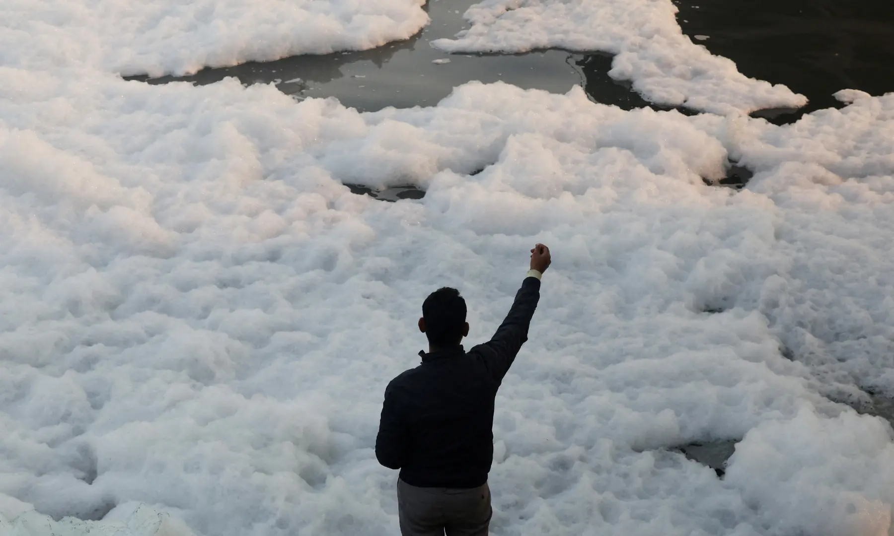 A fisherman uses a string to catch fish through foam on the polluted Yamuna river, on a smoggy morning amid ongoing air pollution in New Delhi, India, on November 21. &mdash; Reuters