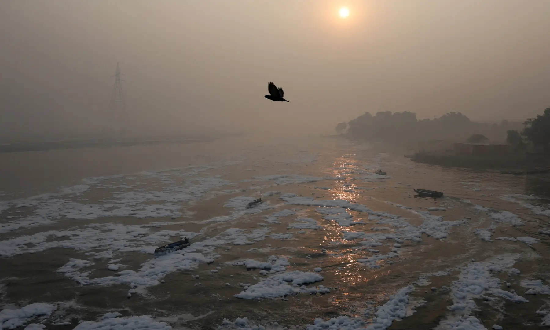 Boats move through foam on the polluted Yamuna river, on a smoggy morning amid ongoing air pollution in New Delhi, India, on November 21. &mdash; Reuters