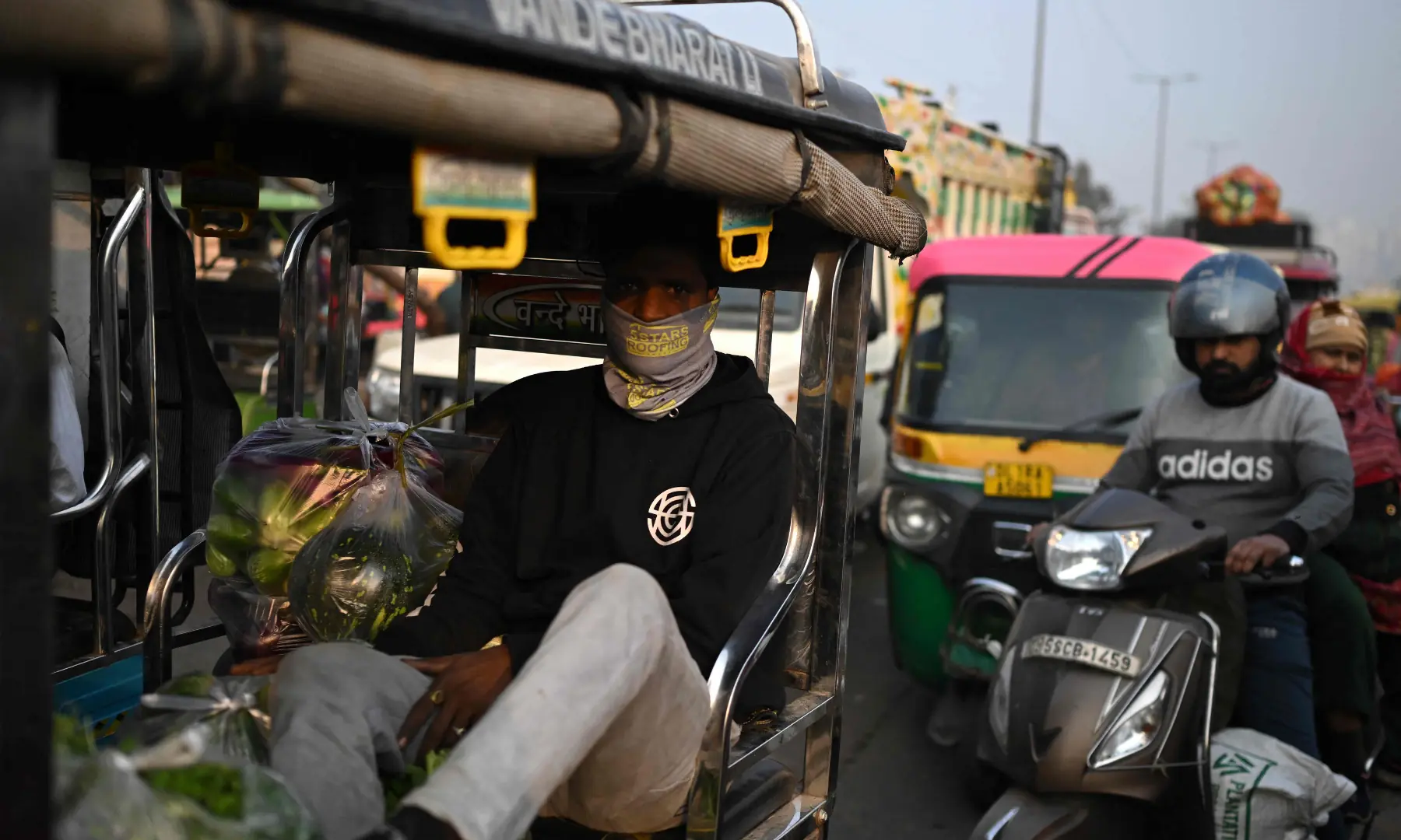 A man covering his face with a cloth commutes on an e-rickshaw amid smoggy conditions in New Delhi on November 21. &mdash; AFP