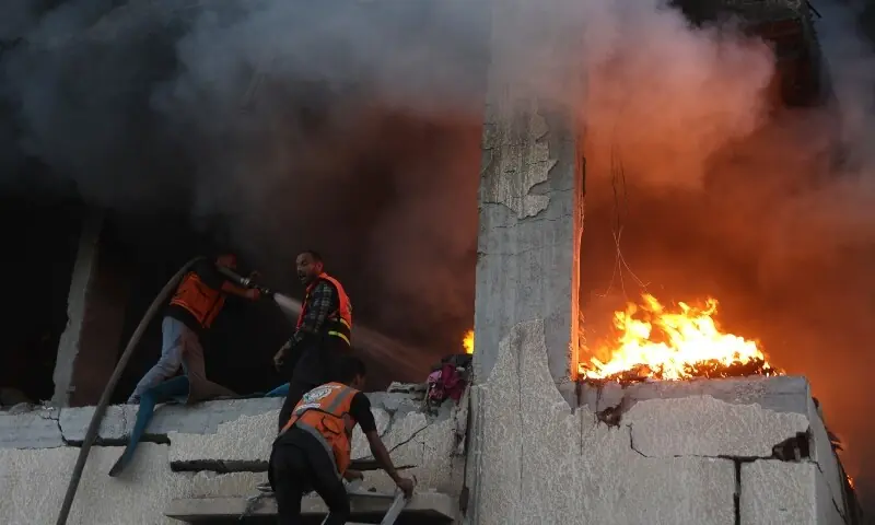 Civil defence personnel search a burning house targeted by Israeli airstrikes in Gaza City, on November 22. &mdash; AFP