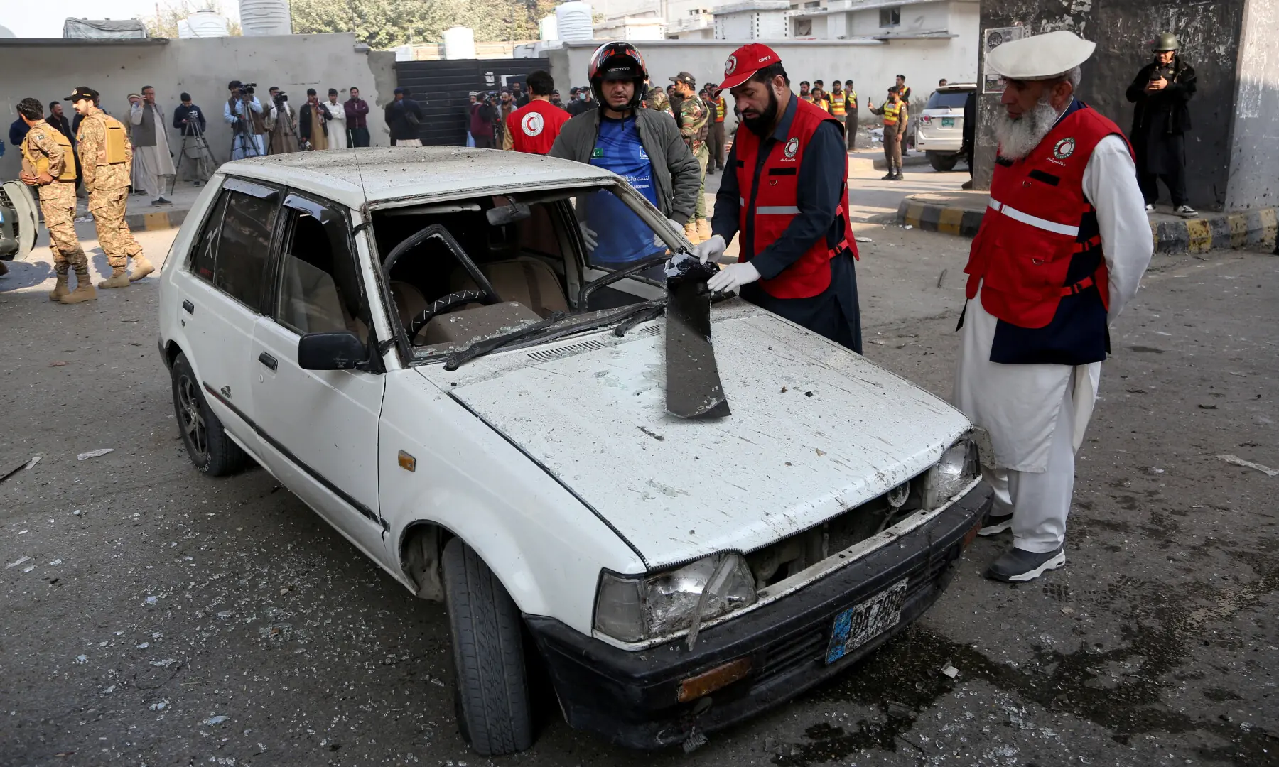 Rescue workers inspect a damaged vehicle after suicide bombers targeted the headquarters of the Federal Constabulary in Peshawar on November 24. — Reuters