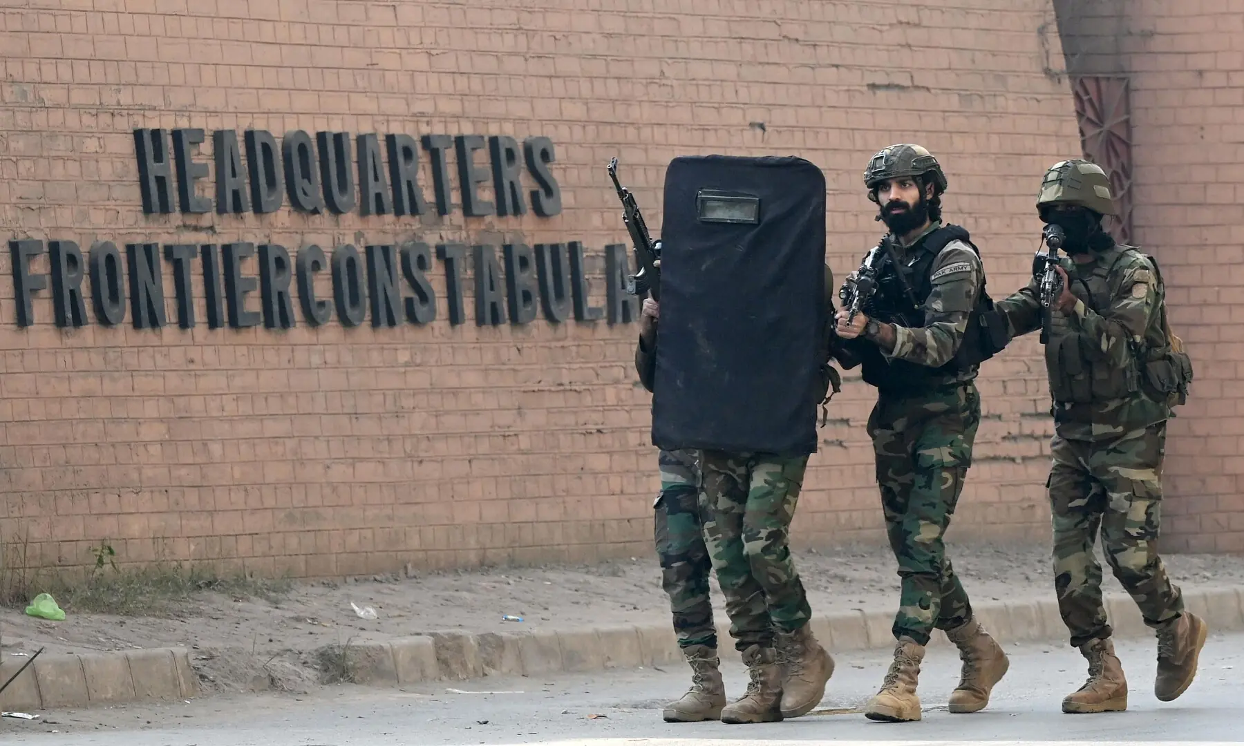 Army personnel take a shield as they move at the suicide bombing site at the Federal Constabulary headquarters in Peshawar on November 24. — AFP