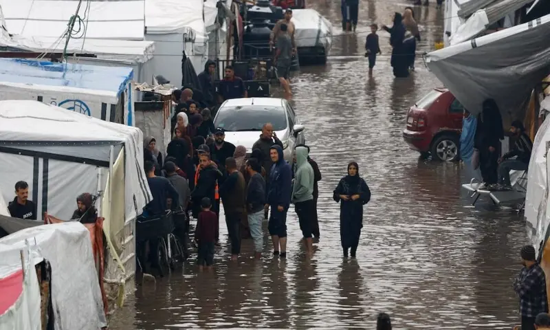 Displaced Palestinians gather next to tents in a flooded area, during a rainy day in Gaza City, November 25. &mdash; Reuters