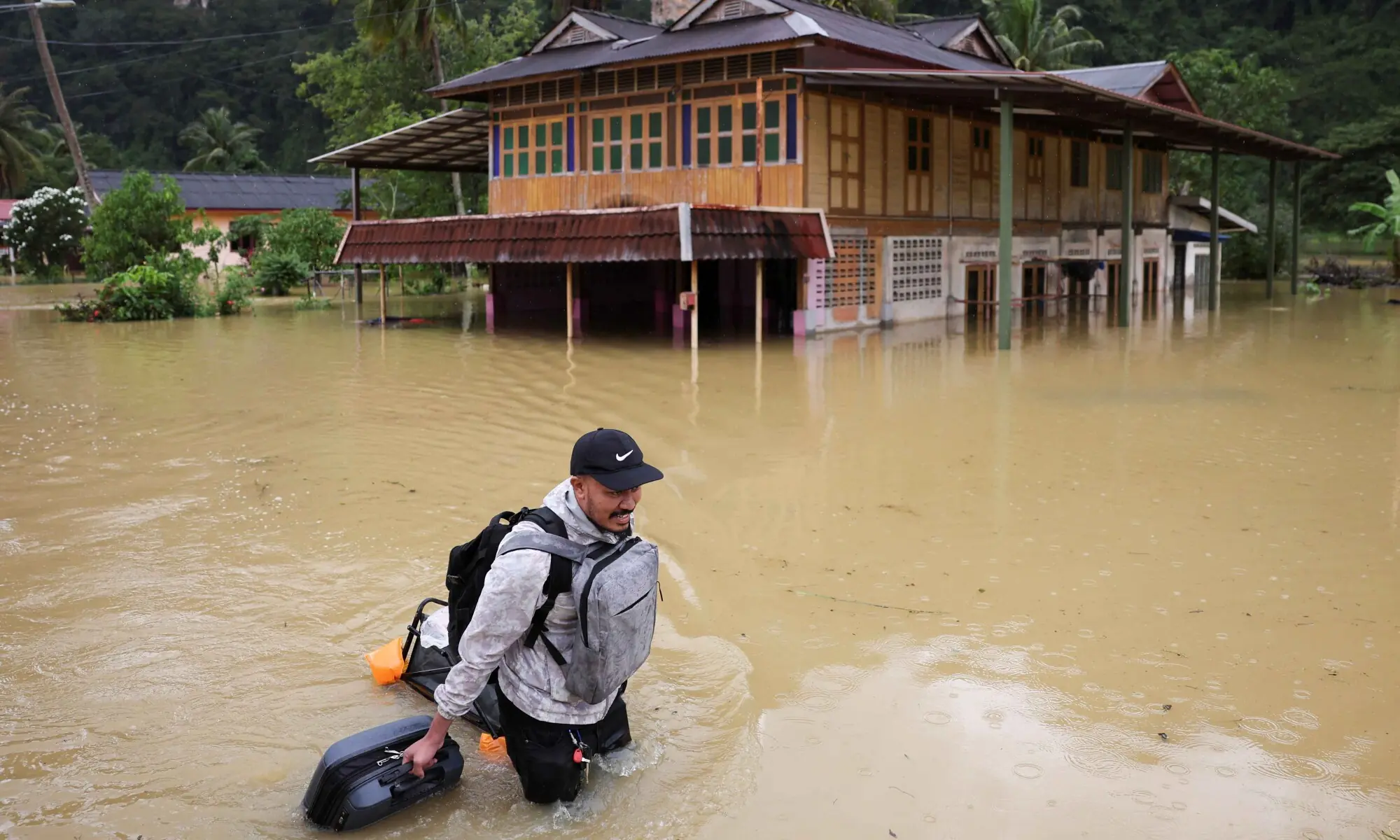 A man wades through floodwater carrying his belongings after heavy rain in the northern states of Malaysia, bordering Thailand, in Kangar, Malaysia on November 26. &mdash; Reuters