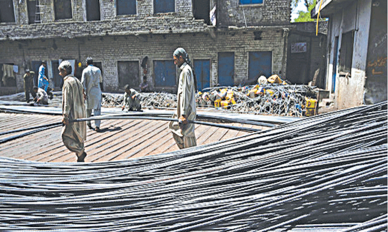 A file photo of workers carrying steel scrap. —AFP