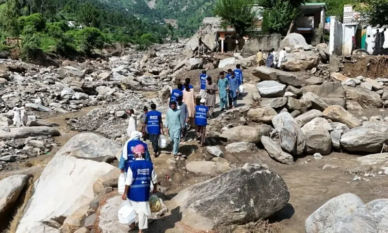 In this aerial picture, volunteers carry aid for residents after flash floods hit Buner district in Khyber Pakhtunkhwa on August 18. — AFP