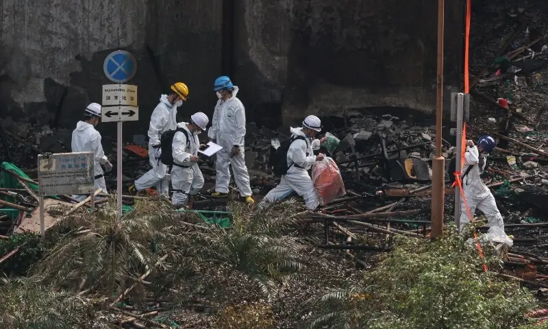 A police officer wearing a protective suit walks with a bag of samples collected at the site of a fire-damaged residential block at Wang Fuk Court housing complex, following a deadly fire on Wednesday, in Tai Po, Hong Kong, China on November 29, 2025. &mdash; Reuters
