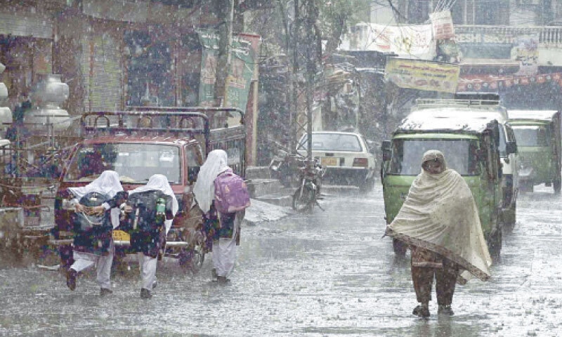 Girls run on a road during rain in Rawalpindi on Tuesday. The temperature dropped following the showers heralding the arrival of winter. &mdash; APP