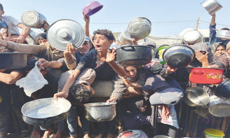 PALESTINIANS receive food from a charity kitchen in Khan Yunis.—Reuters PALESTINIANS receive food from a charity kitchen in Khan Yunis.—Reuters