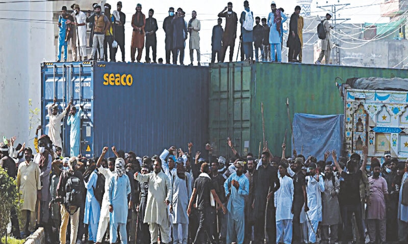  Members of TLP protest after authorities block a road with shipping containers in Lahore on October 10, 2025: the latest ban on TLP, recommended by the Punjab government amid fresh unrest, appears to signal a potentially tougher stance than seen previously | AFP 