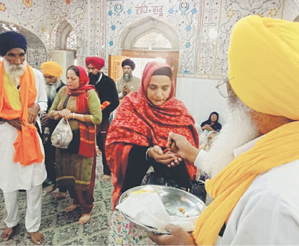 A Sikh pilgrim distributes Prasad (sweet) on the conclusion of Bhog ceremony.