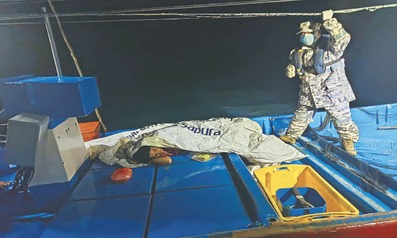 A Malaysian Maritime Enforcement Agency official checks on a survivor rescued by a fishing boat, off the coast of Langkawi.—AFP A Malaysian Maritime Enforcement Agency official checks on a survivor rescued by a fishing boat, off the coast of Langkawi.—AFP