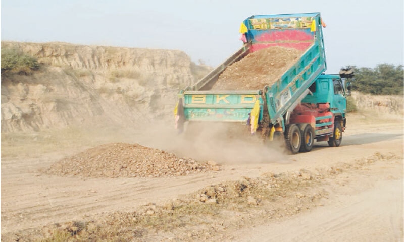 A trailer puts soil on the route of Northern Bypass to make it trafficable. — Dawn