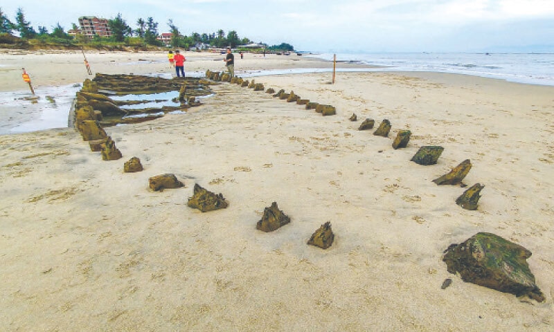 PEOPLE stand next to a centuries-old shipwreck uncovered in the aftermath of Typhoon Kalmaegi last week.&mdash;AFP