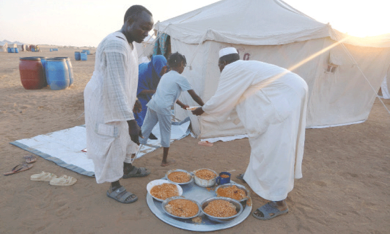 Displaced volunteers deliver a meal of beans to a family displaced by the fighting in Sudan&rsquo;s 
western Darfur region.&mdash;Reuters